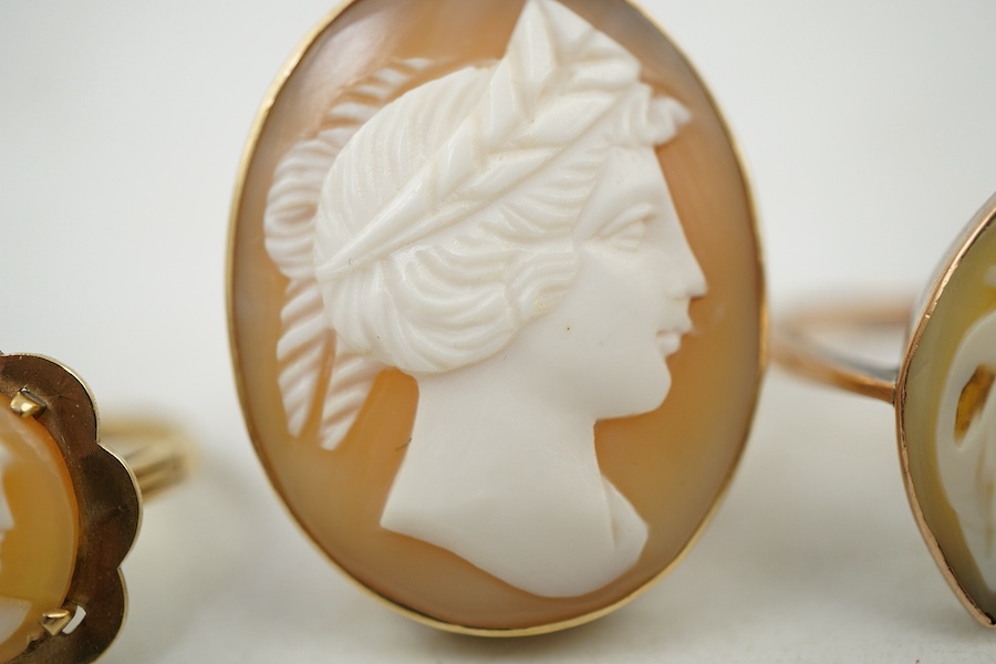 A group of three shell cameo rings, two depicting a classical lady in profile, one of navette-shaped outline depicting a dancing figure, each mounted in gold, two stamped 9ct, largest size V, largest cameo 3 x 2.4cm, com
